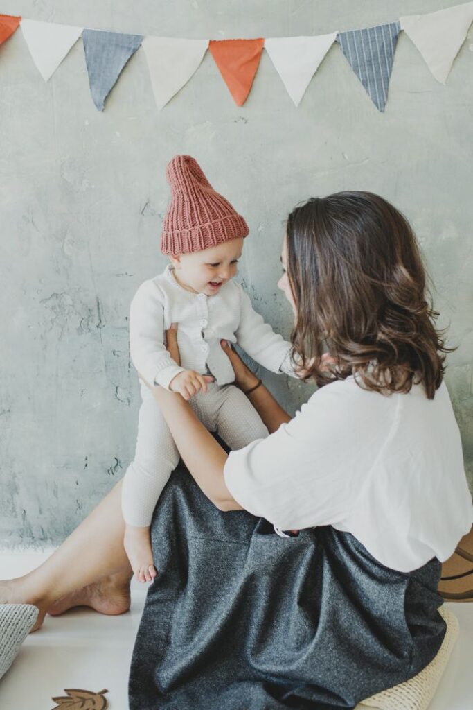 about-us-01 A mother and child share joyful moments together in a cozy indoor setting.
