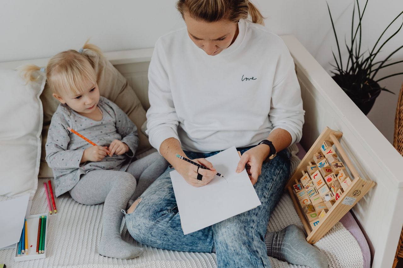 Crafting Captivating Headlines: Your awesome post title goes here A mother guides her child in learning with colorful pencils and alphabet blocks.